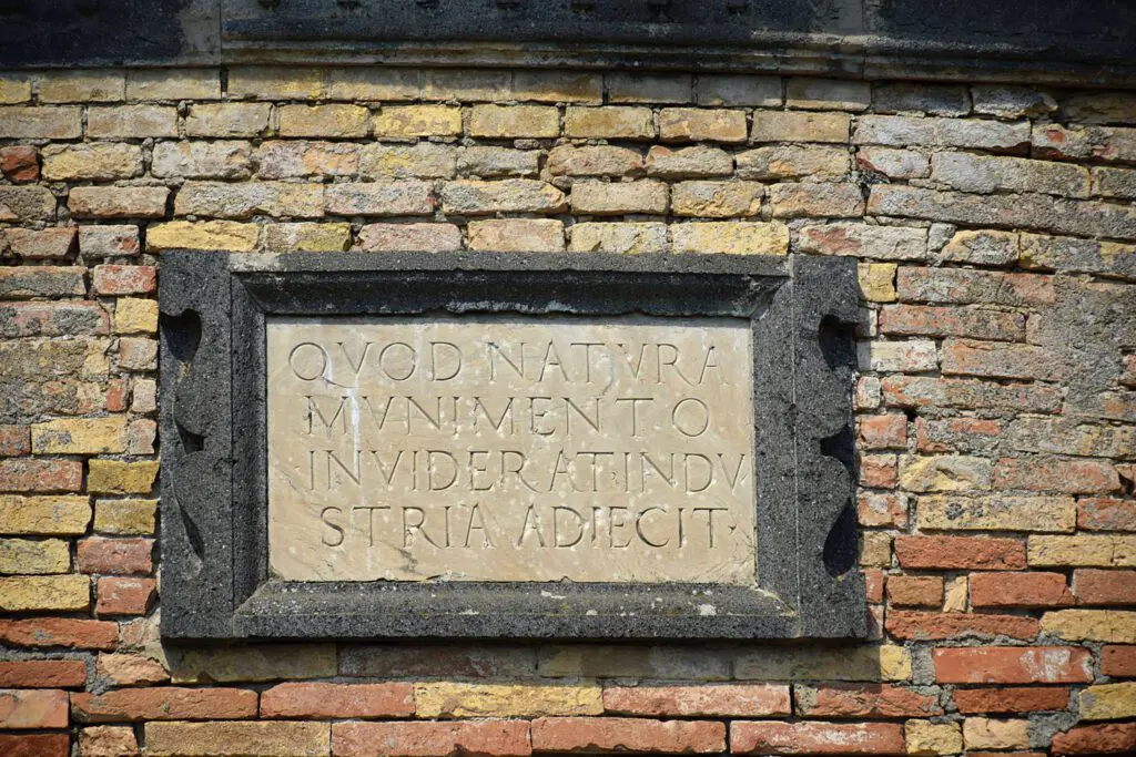 Incisione in latino a fianco del portone di ingresso al pozzo che recita “Quod natura munimento inviderat industria adiecit”.
