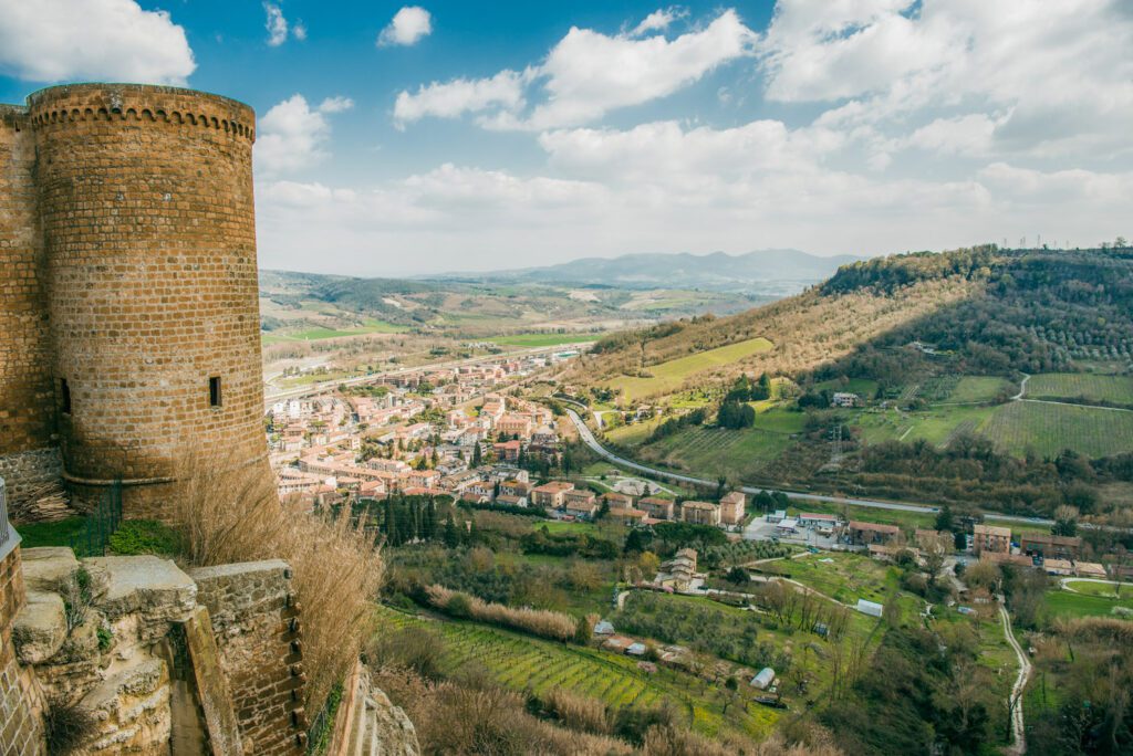 A sinistra è visibile il torrione della Fortezza Albornoz mentre il resto dell’immagine è occupato dalla vista dall’alto della città sottostante e delle campagne umbre.