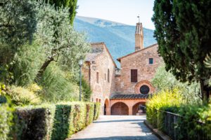 Vista della stradina di arrivo alla chiesa di San Damiano. La strada eè fiancheggiata da siepi, sullo sfondo è visibile la struttura.