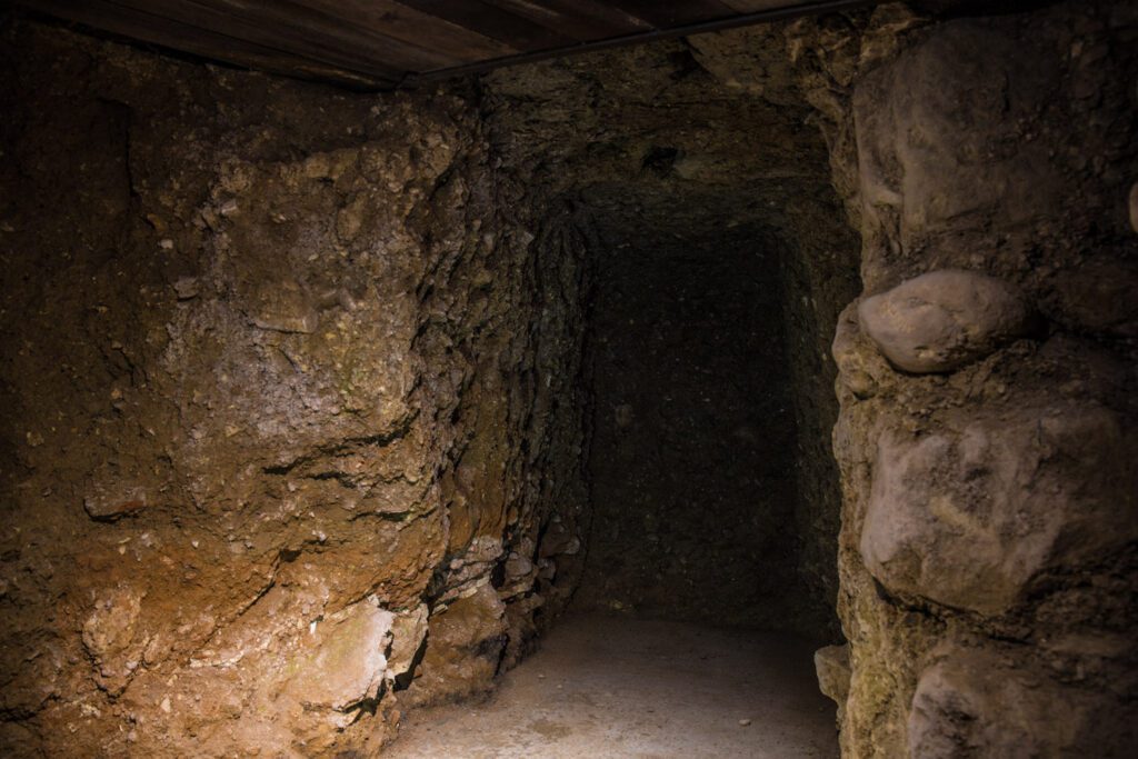 Vista di un cubiculum. Questa era una stanza della domus romana, di cui rimane solo questo angusto spazio poiché, nell'incendio del 40 a.C., la casa è collassata. Nella roccia si inoltra per circa 3 metri uno spazio alto circa 1,5 metri, la cui superficie di calpestio è sollevata rispetto all’attuale. Sulle pareti di roccia sono ancora visibili i segni dell'incendio.