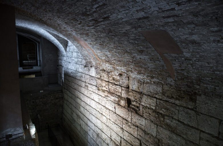 Vista dall'alto del muro di terrazzamento etrusco nella Perugia sotterranea. L'imponente muro, realizzato con grandi conci di travertino, è sormontato da una volta in mattoni.