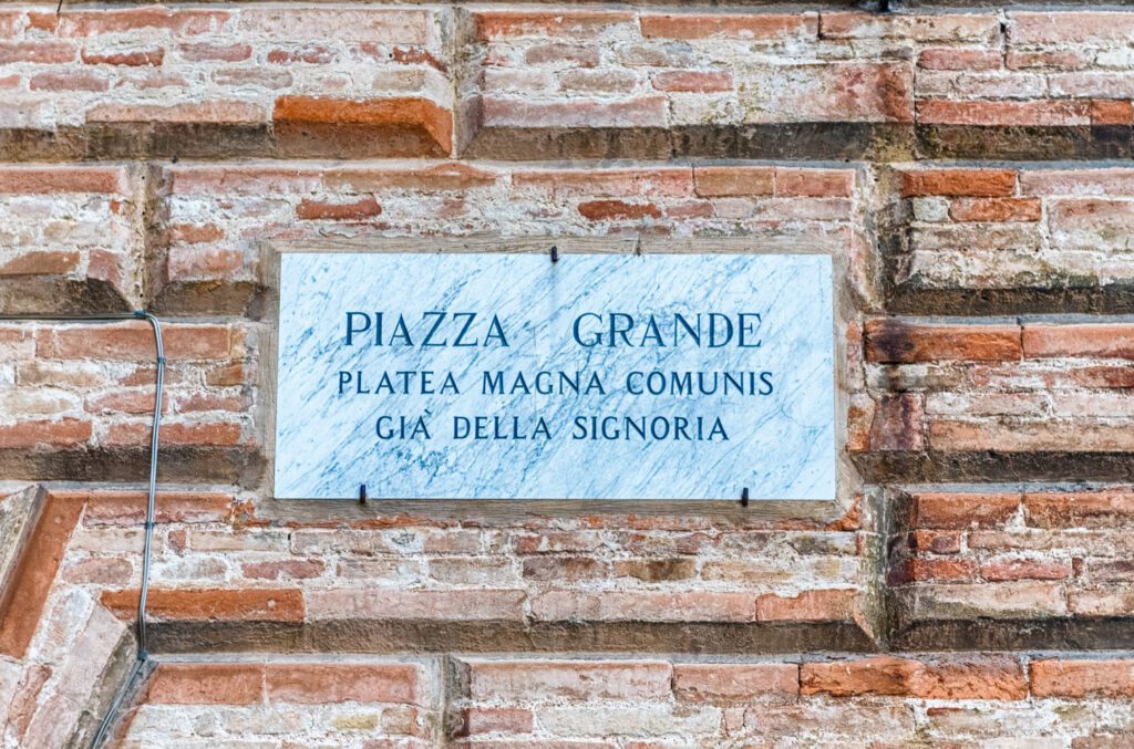 Targa che identifica Piazza Grande e recita “Piazza Grande, Platea magna comunis, Già della Signoria”