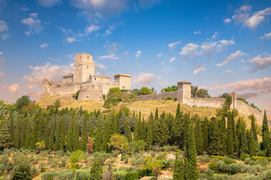 Vista panoramica della Rocca maggiore. Arroccata sul monte si erge imponente staccandosi dal verde dei boschi circostanti.