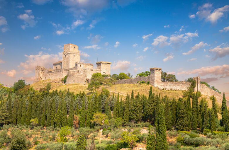 Vista panoramica della Rocca maggiore. Arroccata sul monte si erge imponente staccandosi dal verde dei boschi circostanti.