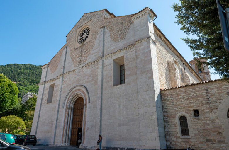 Vista scorciata della facciata romanica di San Francesco a Gubbio. Spiccano il grande portale di ingresso e il rosone.