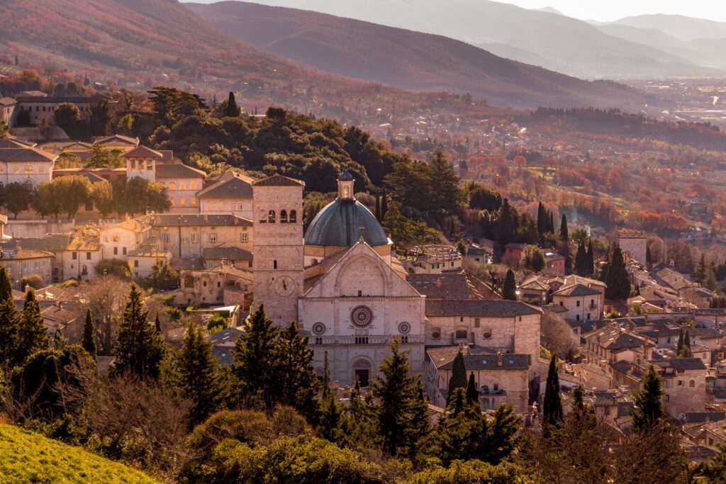 Vista aerea panoramica della cattedrale di San Rufino. La chiesa spicca tra i tetti dell'abitato ed il verde circostante.