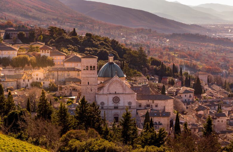 Vista aerea panoramica della cattedrale di San Rufino. La chiesa spicca tra i tetti dell'abitato ed il verde circostante.