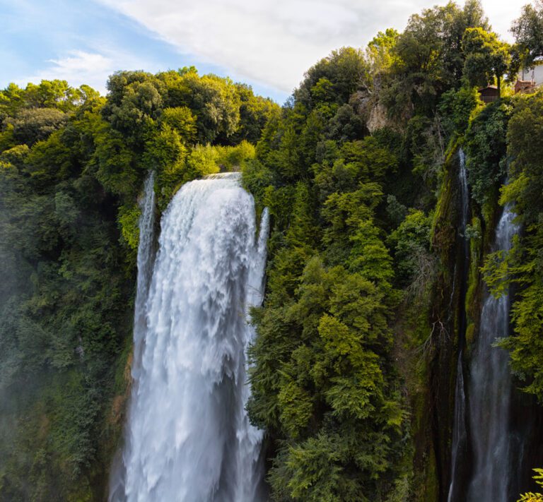 Vista della parte apicale delle Cascate delle Marmore, a Terni. L’acqua scende velocemente da pendici coperte di fitto bosco verdissimo.