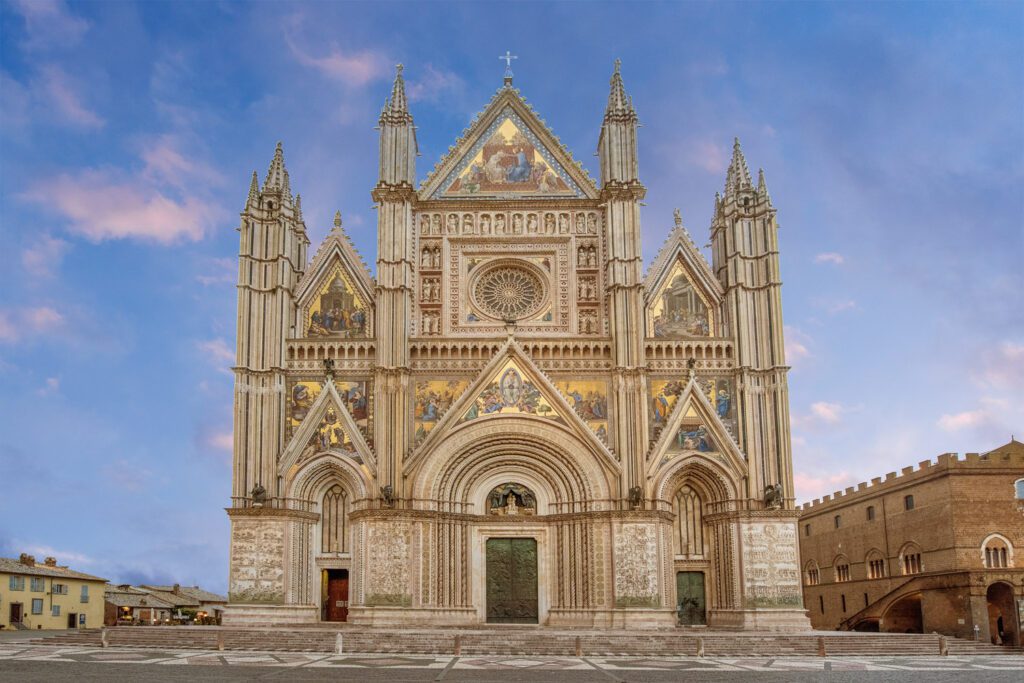 Vista frontale della facciata tricuspidale del Duomo di Orvieto. La facciata è decorata da sculture e mosaici.