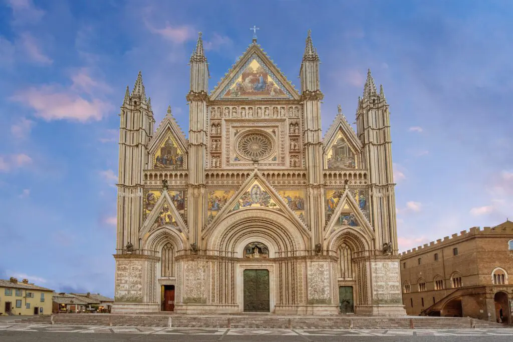 Vista frontale della facciata tricuspidale del Duomo di Orvieto. La facciata è decorata da sculture e mosaici.