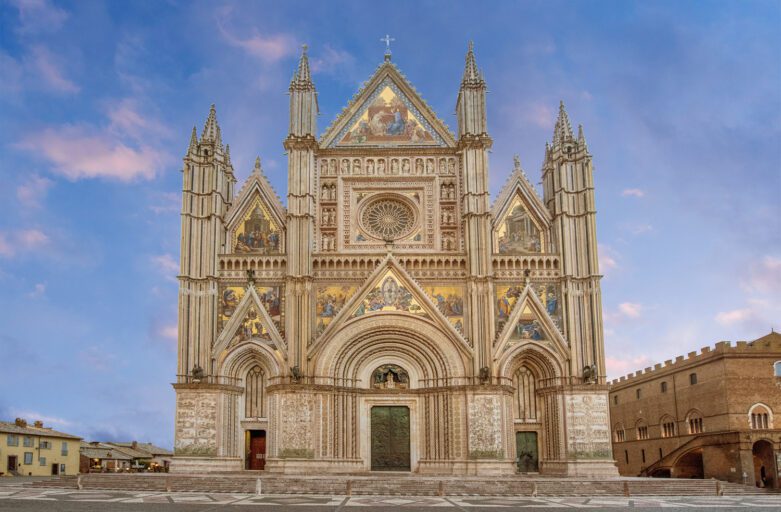 Vista frontale della facciata tricuspidale del Duomo di Orvieto. La facciata è decorata da sculture e mosaici.