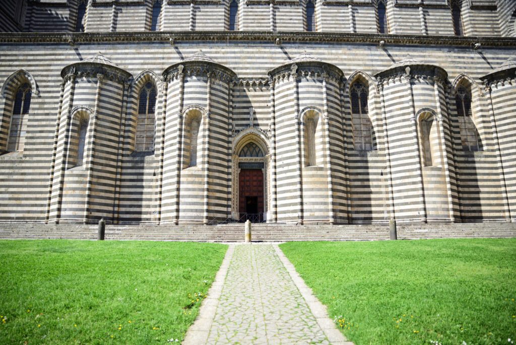Vista frontale del fianco della cattedrale decorato con marmo bicromo bianco e nero a fasce orizzontali e precorso da absidiole.