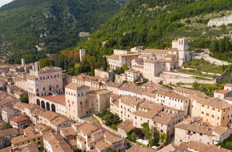 Gubbio: vista aerea della città arroccata sulle verdi pendici del monte coperte di boschi. Spiccano Piazza Grande e il Palazzo dei Consoli.