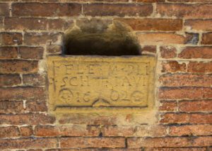 Dettaglio della Buca per le elemosine sulla facciata di Santa Maria dei Bianchi. Un incavo nel muro è chiuso, lasciando solo uno spazio per l'inserimento delle elemosine, da una lastra di pietra incisa .