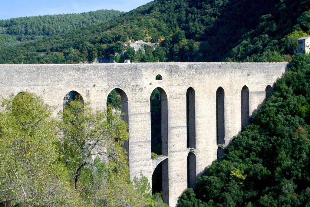 Vista Scorciata del Ponte delle Torri dal lato della rocca. Sono visibili i colossali archi che sorreggono l’antico acquedotto immerso nel verde.