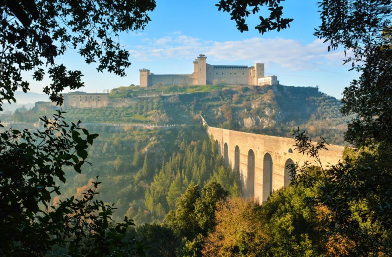 Vista panoramica del Ponte delle Torri. Guardando da Monteluco si vedono, incorniciati dalle fronde della vegetazione, il Ponte delle Torri e la Rocca di Albornoz in cima a Colle Sant'Elia.