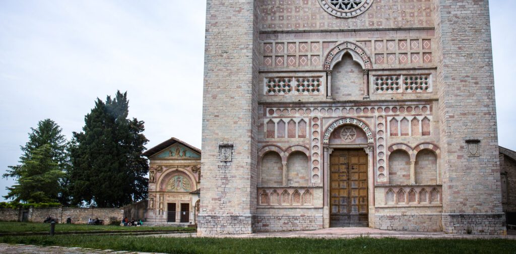 Vista della imponente facciata di San Francesco al Prato, alla sua sinistra il prato su cui sorge e sullo sfondo, poco distante e che affaccia sempre sul prato, la chiesa di San Bernardino.