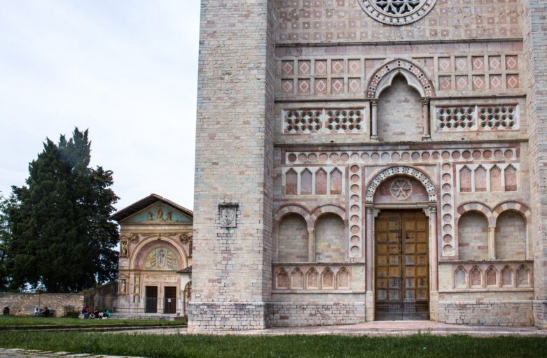 Vista della imponente facciata di San Francesco al Prato, alla sua sinistra il prato su cui sorge e sullo sfondo, poco distante e che affaccia sempre sul prato, la chiesa di San Bernardino.