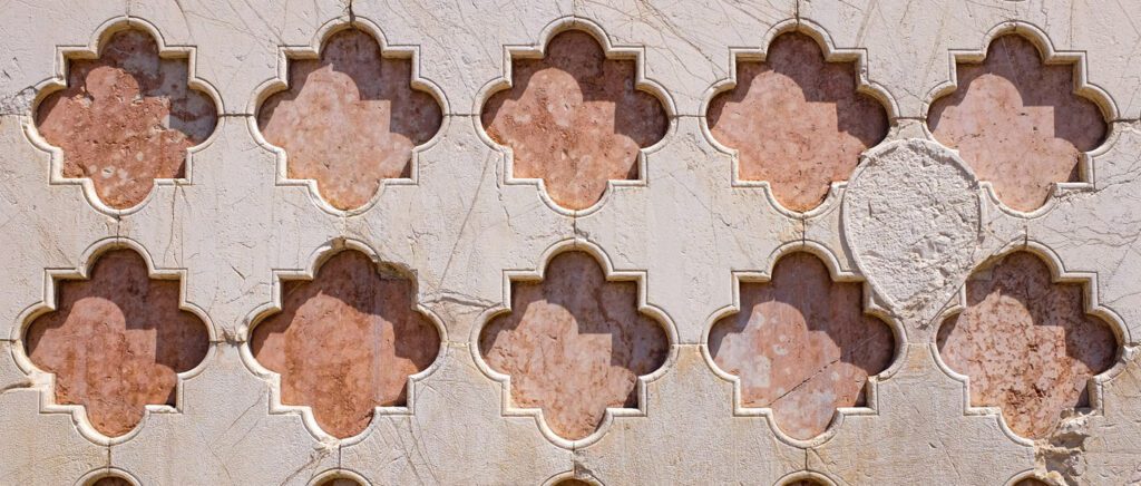 Dettaglio della facciata della Cattedrale di San Lorenzo che da su Piazza 4 Novembre. Marmo bianco con serie di rombi lobati di colore rosa.