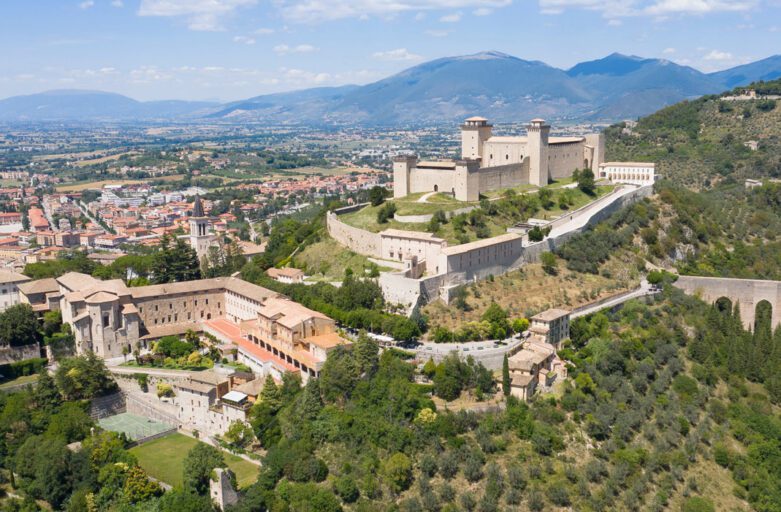 Spoleto: vista aerea della città, con Rocca Albornoz in cima alla collina e Ponte delle Torri immersa nel verde sulla destra.