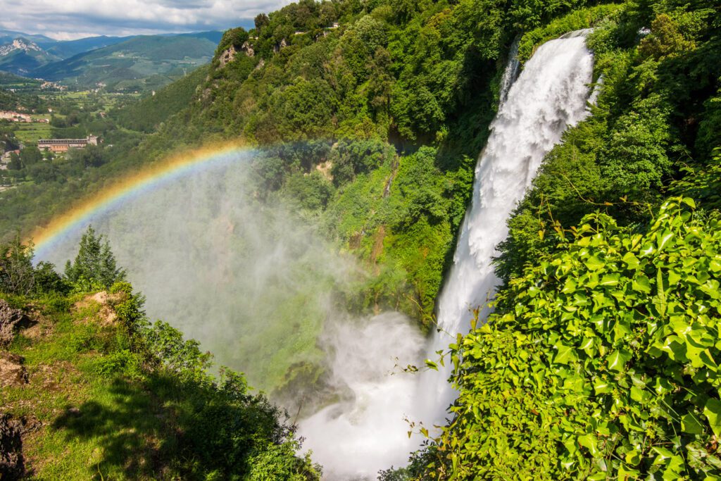 Vista dall'alto delle Cascate delle Marmore. Il vapore acqueo che si solleva per via dello scroscio dell'acqua crea, con la luce, un bellissimo arcobaleno che si affaccia sulla vallata sottostante.