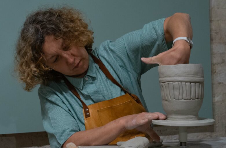 Immagina di Monica, l'arte terapeuta, che modella dell'argilla per creare un vaso.