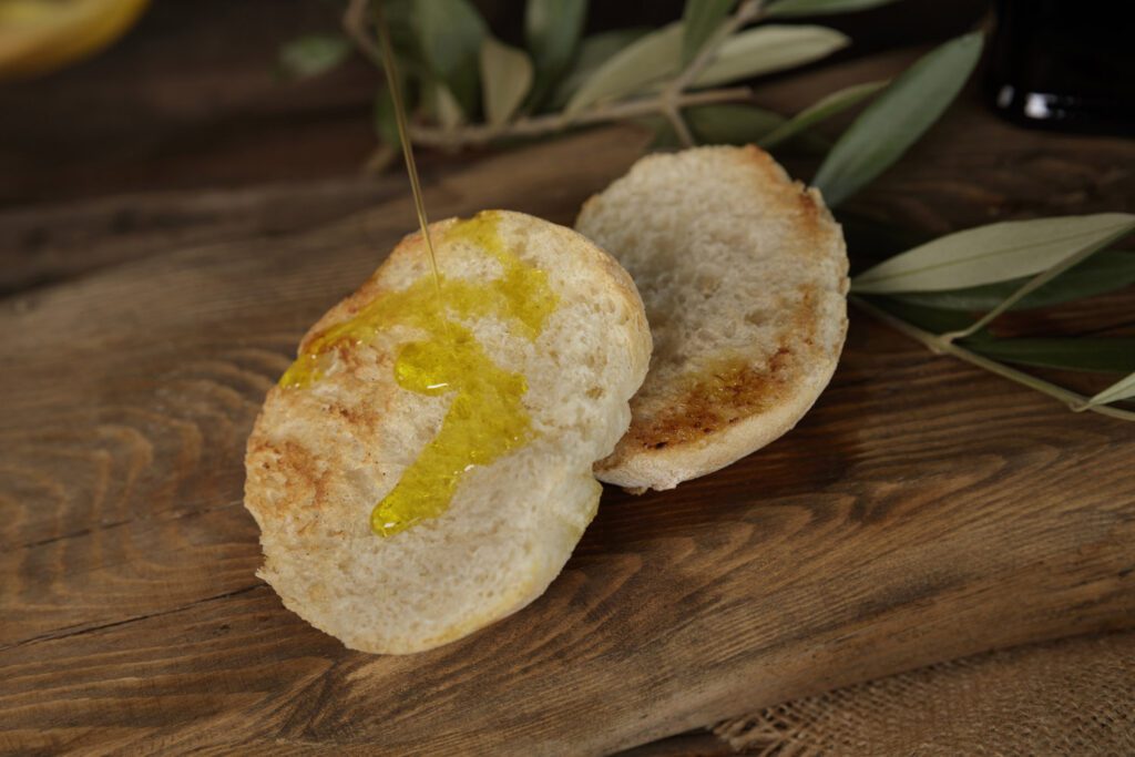 Close-up image of two bruschette, roasted slices of bread, on which extra virgin olive oil DOP from Umbria is poured.