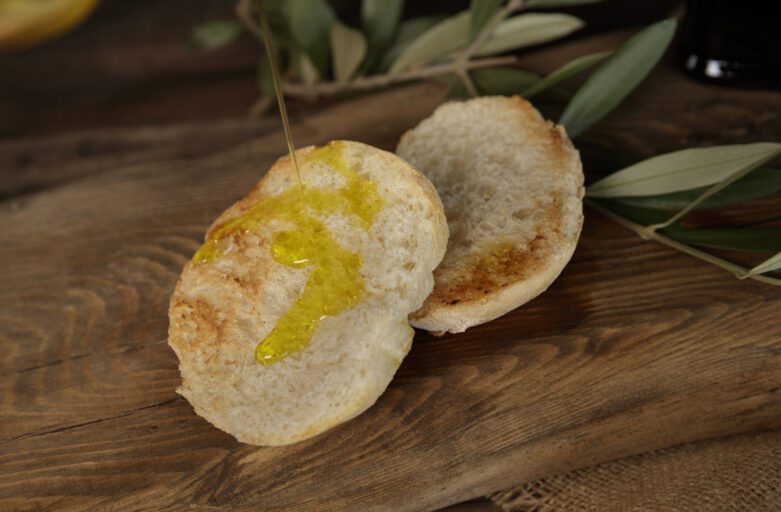 inquadratura ravvicinata di due bruschette, fette di pane arrostite, sulle quali viene versato sopra dell’olio extravergine di oliva DOP dell’Umbria.