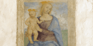 Dettaglio dell'affresco raffigurante una Madonna seduta su un banco di legno, che sembra sporgere dal muro, ritratta nell’atto di sorreggere il Bambino in piedi sul suo ginocchio destro. Il Bambino è aggrappato con la mano sinistra alla tunica della madre, come per tenersi meglio in piedi. Nella parte bassa dell’affresco compare l’iscrizione “Agniolus Toni Angeli fecit fieri MDXXII”.