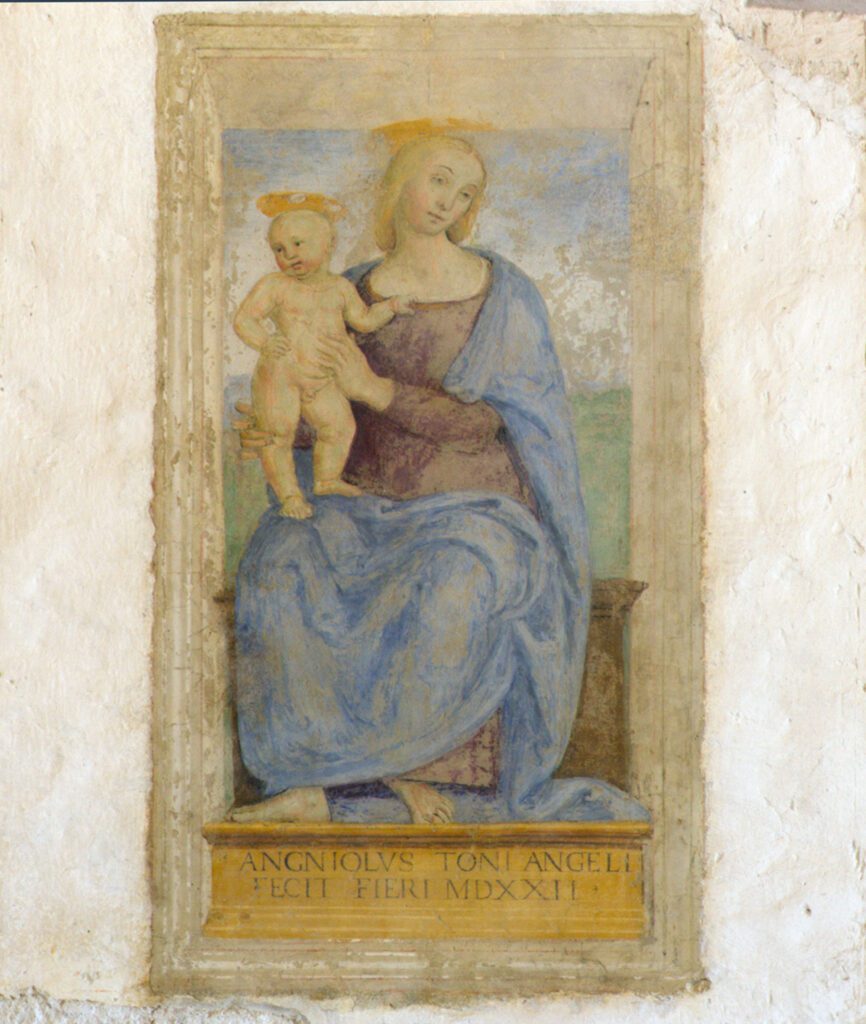 Detail of the fresco depicting the Virgin Mary seated on a wooden bench, which seems to protrude from the wall. She is portrayed in the act of supporting the Child standing on her right knee. The Child is clinging with his left hand to his mother's tunic, as if to better hold himself up. In the lower part of the fresco is the inscription 'Agniolus Toni Angeli fecit fieri MDXXII'.