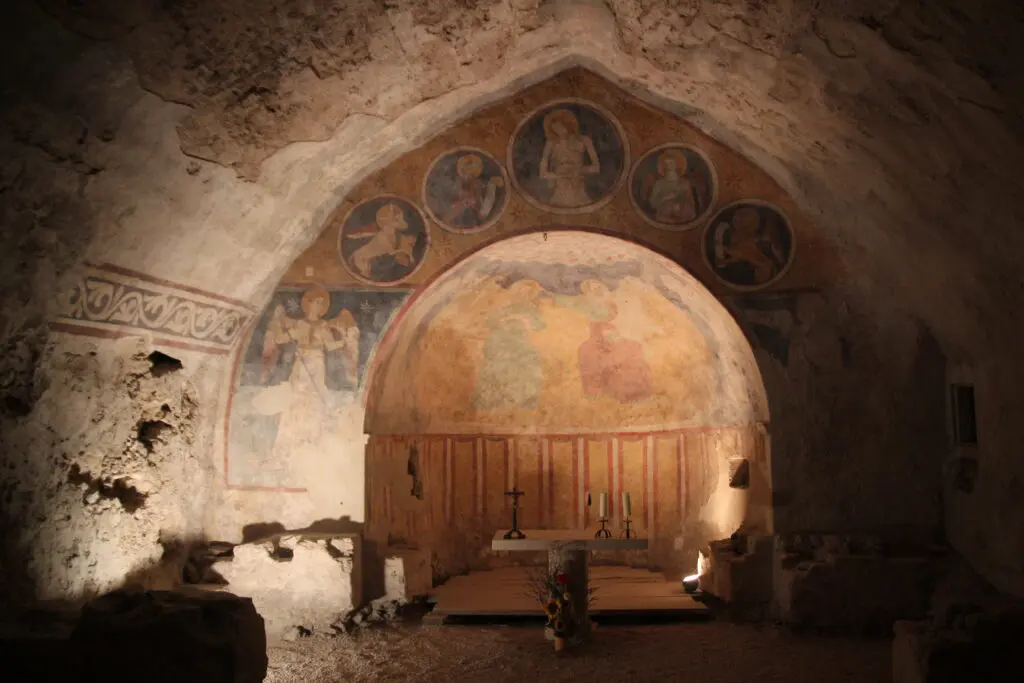 Foto dell’interno della Chiesa di Santa Maria della Rupe che fa parte del percorso di Narni Sotterranea. Costruita tra il XII e il XIII secolo, la Chiesa è stata costruita all’interno di una cavità rocciosa e formata da una sala rettangolare absidata, coperta da una volta a sesto acuto irregolare e decorata con affreschi a tema sacro.